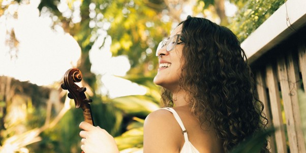 Camila Alves sorrindo com o violino ao ar livre