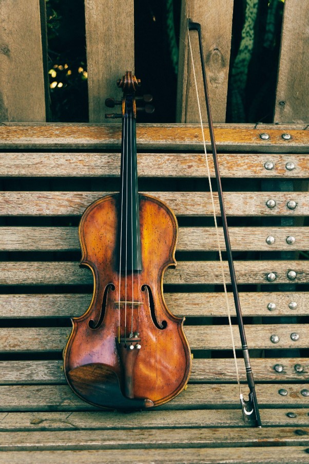 Violino e arco apoiados em um banco de madeira